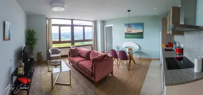 a living room with a pink couch and a kitchen at Apartamentos Buenavista Tineo in Tineo