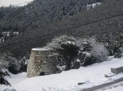 a stone pillar in the snow next to a mountain at Casa de aldea Amezaga in Taramundi