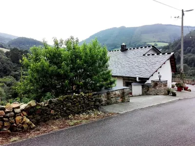 a house with a stone wall next to a road at Casa de aldea Amezaga in Taramundi