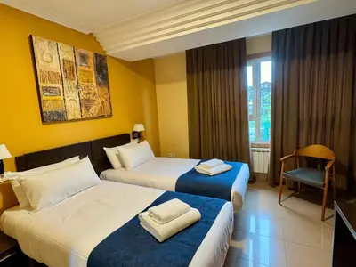 a hotel room with two beds and a chair at Hotel Reigosa in Pontevedra