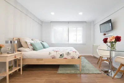 a white bedroom with a bed and a table at NC APARTMENT in Santiago de Compostela