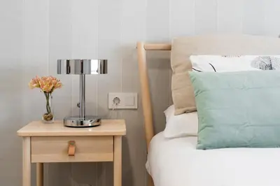 a bed with a table with a vase of flowers on a night stand at NC APARTMENT in Santiago de Compostela