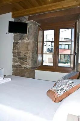 a bedroom with a large bed with a stone wall at PENSION SERRANO in Sarria