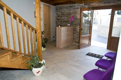 a hallway with purple chairs and a wooden staircase at PENSION SERRANO in Sarria