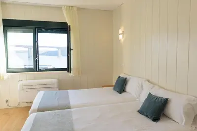 a bedroom with two beds and a window at Hotel Alda Fogar do Mariñeiro in Ribadeo