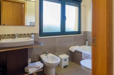 a bathroom with a sink and a toilet and a window at Hotel Alda Fogar do Mariñeiro in Ribadeo