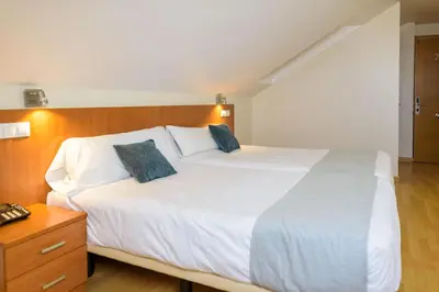 a bedroom with a large white bed with blue pillows at Hotel Alda Fogar do Mariñeiro in Ribadeo