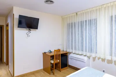a bedroom with a bed and a desk and a tv on a wall at Hotel Alda Fogar do Mariñeiro in Ribadeo