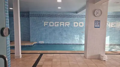 a swimming pool in a building with a clock on the wall at Hotel Alda Fogar do Mariñeiro in Ribadeo