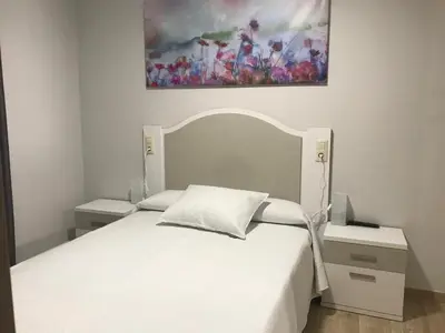 a bedroom with a white bed and a painting on the wall at Pensión CHE in O Pedrouzo