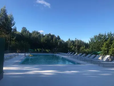 a swimming pool with tables and chairs in a park at Pensión CHE in O Pedrouzo