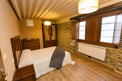 a bedroom with a bed and a stone wall at Apartamentos Casa Mateo in Navia
