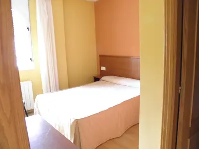 a small bedroom with a bed and a window at Hotel La Mora in Villaseca de Laciana
