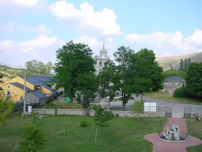 a large white building with a church in the distance at Hotel La Mora in Villaseca de Laciana