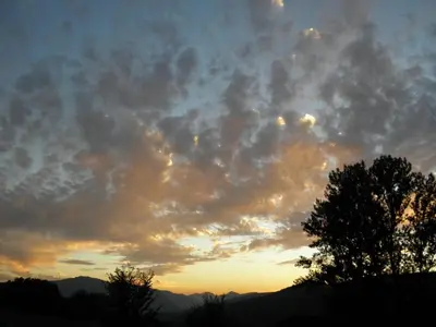 a cloudy sky at sunset with a tree in the foreground at Hotel La Mora in Villaseca de Laciana