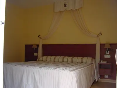 a bedroom with a large bed with white sheets at Hotel La Mora in Villaseca de Laciana