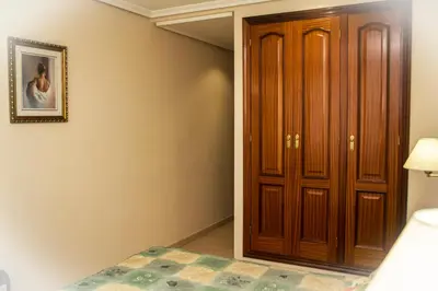 a bedroom with a bed and a wooden closet at HOTEL LORENZO in Carballino
