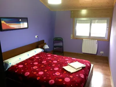 a bedroom with a bed with red sheets and two towels at M Ramona Reja Díaz in Lourenzá