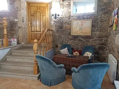 a living room with blue chairs and a stone wall at Casa Rosalía in Silleda