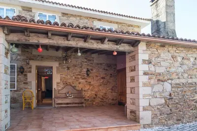 an outdoor patio with a stone wall and a bench at Casa Rosalía in Silleda