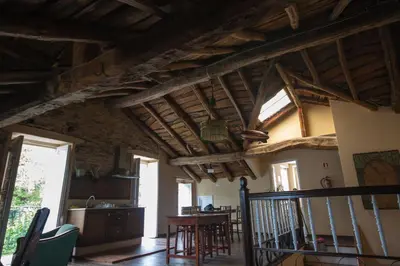 a living room with wooden ceilings and a table at CASA PELTRE in Sarria