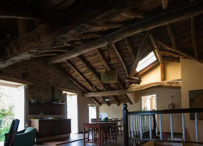 a living room with wooden ceilings and a table at CASA PELTRE in Sarria