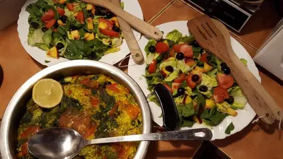 a table with two plates of salad and a pot of food at Casa Rural Las Águedas in Murias de Rechivaldo