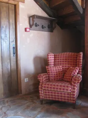 a red checkered chair sitting in a room with a wooden ceiling at Casa Rural Las Águedas in Murias de Rechivaldo