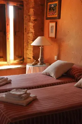 two beds in a room with a lamp on a table at Casa Rural Las Águedas in Murias de Rechivaldo