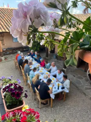 a group of people sitting at a long table with flowers at Albergue Rural Las Águedas in Murias de Rechivaldo