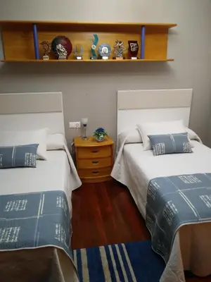 a bedroom with two beds and a wooden floor at Apartamento La Real in Caldas de Reis