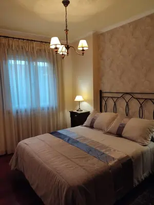 a bedroom with a large bed with a chandelier at Apartamento La Real in Caldas de Reis