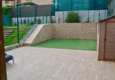 a patio with a retaining wall and a green lawn at Chalet adosado en Costa Miño a un paso de la playa in Miño