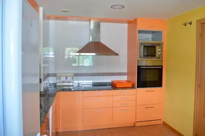 a kitchen with orange cabinets and a stove at Chalet adosado en Costa Miño a un paso de la playa in Miño
