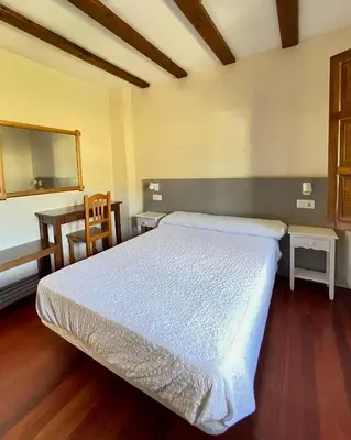 a bedroom with a bed and a table and a chair at El Mirador de Sanabria in Galende