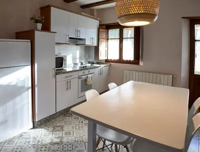a kitchen with white cabinets and a table with chairs at El Mirador de Sanabria in Galende