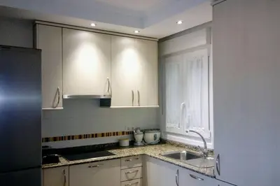 a kitchen with white cabinets and a sink at Foz vacaciones a orillas del mar in Foz