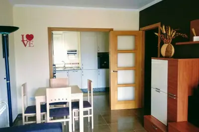 a kitchen with a table and chairs and a refrigerator at Foz vacaciones a orillas del mar in Foz