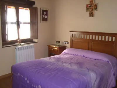 a bedroom with a purple bed and a window at Hotel Rural La Veleta in Murias de Rechivaldo