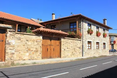 a stone building with wooden doors on a street at Hotel Rural La Veleta in Murias de Rechivaldo
