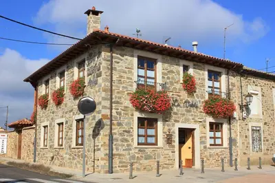 a stone building with flower boxes on the windows at Hotel Rural La Veleta in Murias de Rechivaldo