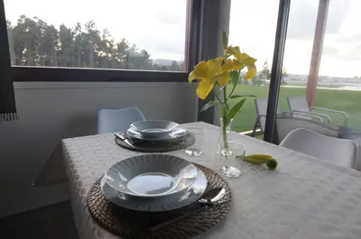 a table with plates and a vase with a yellow flower at Cabanas Da Barcela in Barreiros