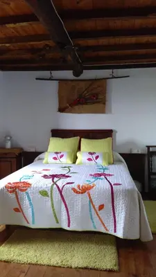a bedroom with a bed with a white blanket and yellow pillows at A Minguxaina in Ribadeo