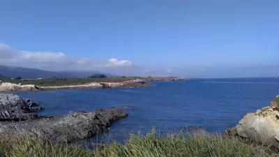 a large body of water with rocks in the foreground at A Minguxaina in Ribadeo