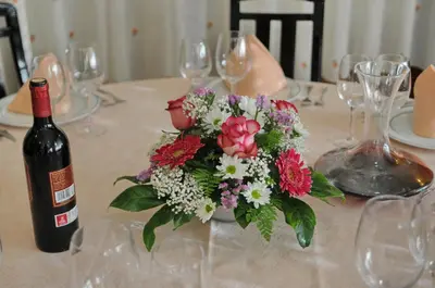 a table with a bottle of wine and a vase of flowers at Hotel Garcas in Lavacolla