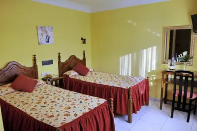 a bedroom with two beds and a chair and a window at Hotel Garcas in Lavacolla