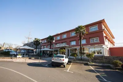 a white car parked in a parking lot in front of a building at Hotel Garcas in Lavacolla