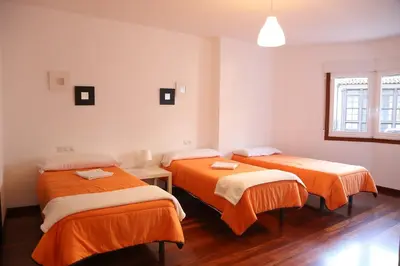 a room with two beds with orange sheets at PENSION DE PEREGRINOS LA MODERNA in Caldas de Reis