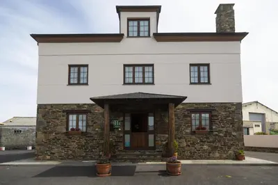 a large white house with a stone building at Hotel Rural As Laguas in Tapia de Casariego
