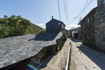 an alley with a stone building next to a street at Hotel Rural Valle de Ancares in Pereda de Ancares